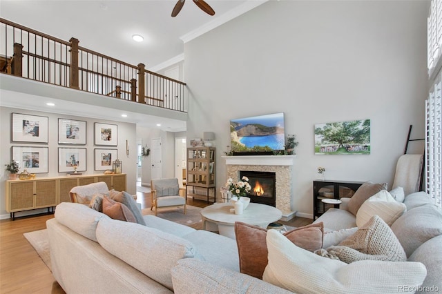 7027 Chestnut Hill St, Highlands Ranch, CO 80130 - living area featuring a high ceiling, ceiling fan, light wood finished floors, a glass covered fireplace, and crown molding