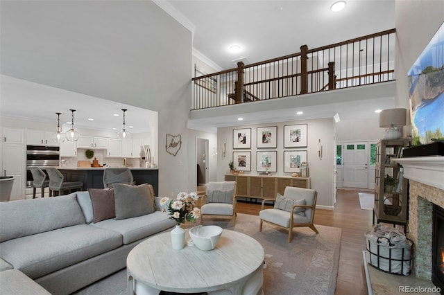 7027 Chestnut Hill St, Highlands Ranch, CO 80130 - living area featuring a high ceiling, ornamental molding, wood finished floors, a fireplace, and recessed lighting