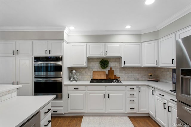 7027 Chestnut Hill St, Highlands Ranch, CO 80130 - kitchen featuring appliances with stainless steel finishes, crown molding, light countertops, white cabinetry, and tasteful backsplash