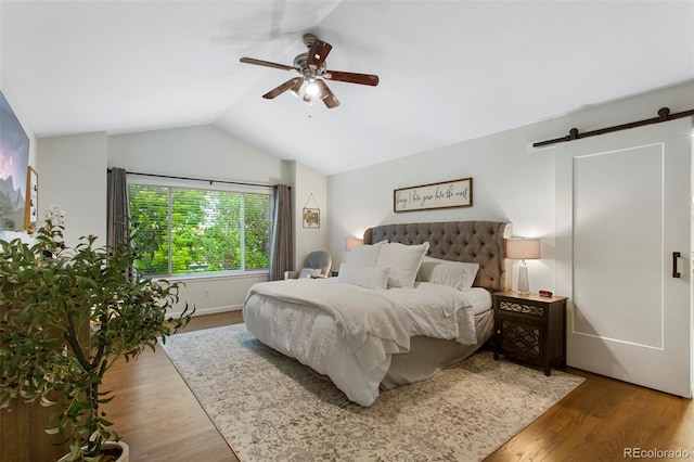 7027 Chestnut Hill St, Highlands Ranch, CO 80130 - bedroom featuring a barn door, vaulted ceiling, wood finished floors, and a ceiling fan