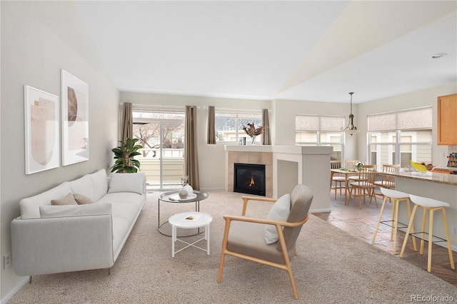 living room with lofted ceiling, a healthy amount of sunlight, light carpet, and a tile fireplace