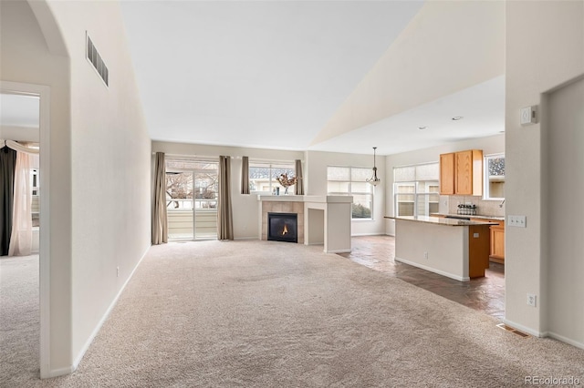 unfurnished living room featuring a tiled fireplace, dark carpet, and high vaulted ceiling