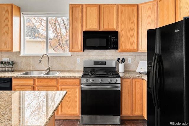 kitchen featuring sink, decorative backsplash, light stone counters, and black appliances