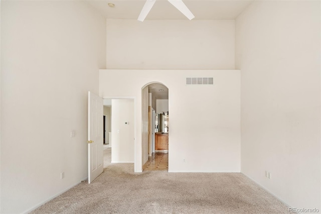 empty room featuring light colored carpet and a towering ceiling