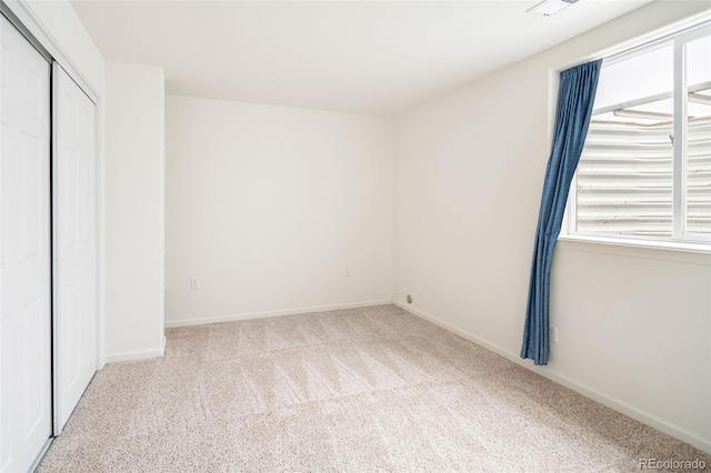 unfurnished bedroom with light colored carpet and a closet