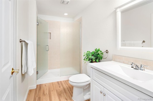 bathroom with wood-type flooring, toilet, an enclosed shower, and vanity