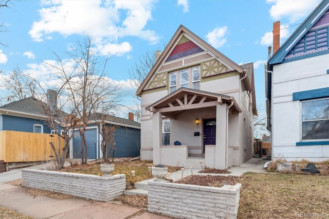 victorian-style house featuring fence, an outdoor structure, and stucco siding