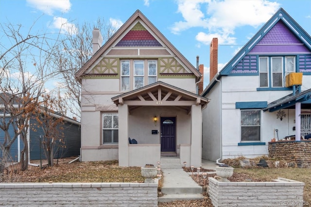 victorian-style house featuring a chimney and stucco siding