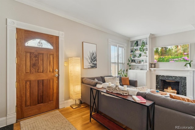 living room with light wood-type flooring, a fireplace, and ornamental molding