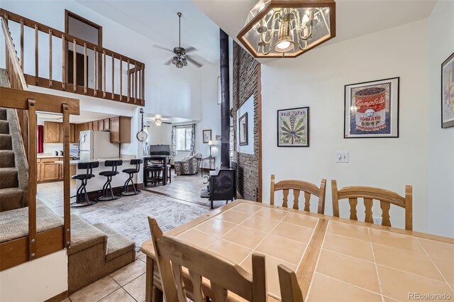 195 Briggs St, Erie, CO 80516 - dining area with stairway, light tile patterned floors, ceiling fan with notable chandelier, a wood stove, and a towering ceiling