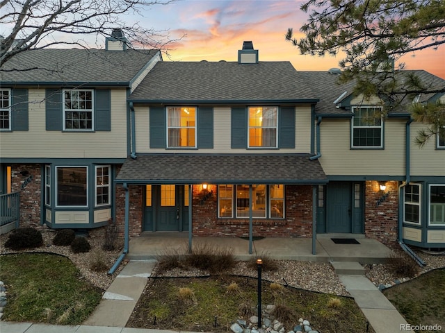7068 E Briarwood Dr, Centennial, CO 80112 - townhome / multi-family property featuring a chimney, brick siding, a shingled roof, and covered porch