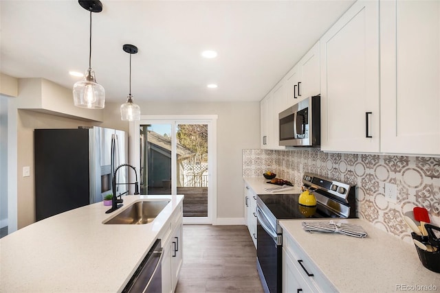 kitchen featuring appliances with stainless steel finishes, a sink, white cabinetry, and tasteful backsplash