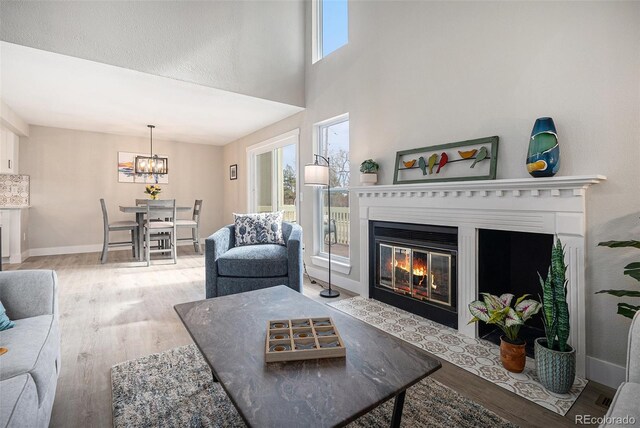 living room featuring a fireplace with flush hearth, baseboards, and wood finished floors