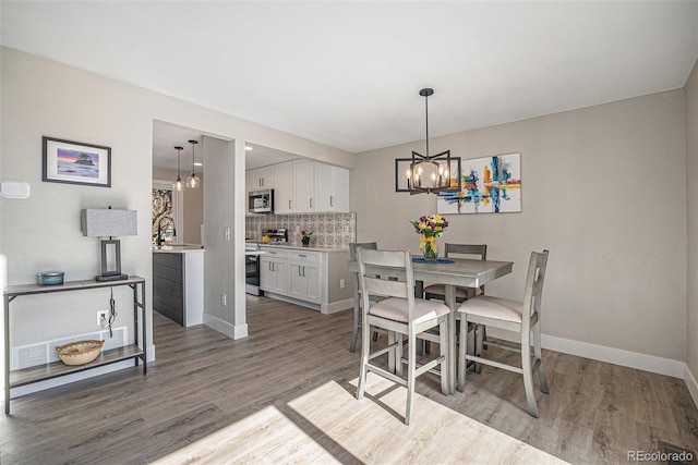 dining area with light wood-style flooring, baseboards, and an inviting chandelier