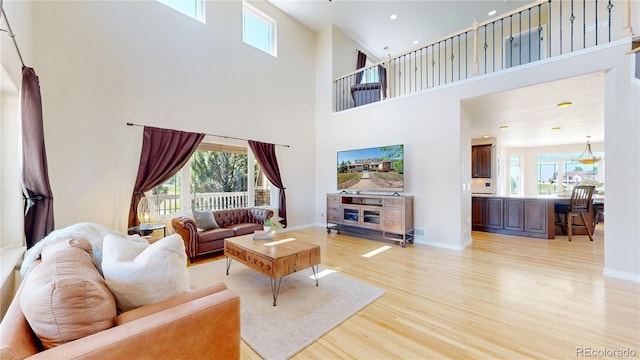 9353 E 146th Ave, Brighton, CO 80602 - living area featuring light wood-style flooring, a towering ceiling, healthy amount of natural light, and recessed lighting
