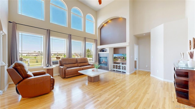 9353 E 146th Ave, Brighton, CO 80602 - living room featuring a high ceiling, a glass covered fireplace, and light wood-type flooring