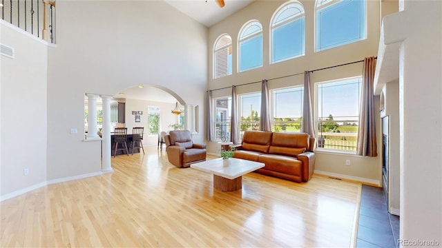 9353 E 146th Ave, Brighton, CO 80602 - living room featuring arched walkways, decorative columns, plenty of natural light, wood finished floors, and a high ceiling