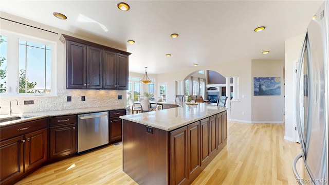 9353 E 146th Ave, Brighton, CO 80602 - kitchen with stainless steel appliances, arched walkways, light wood finished floors, tasteful backsplash, and light stone countertops