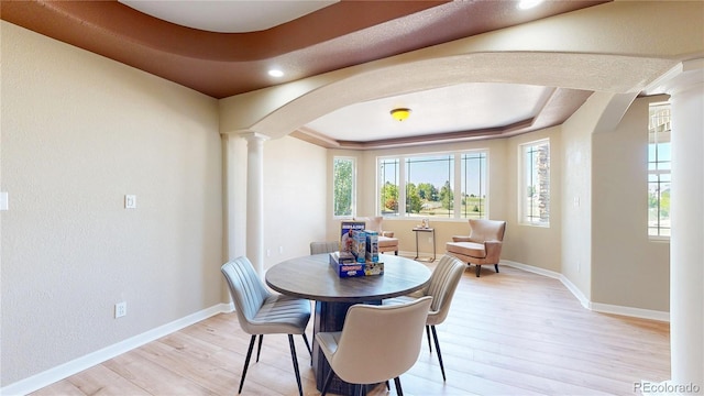 9353 E 146th Ave, Brighton, CO 80602 - dining room featuring arched walkways, a raised ceiling, decorative columns, light wood-style floors, and recessed lighting