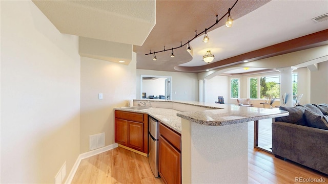 9353 E 146th Ave, Brighton, CO 80602 - kitchen with open floor plan, brown cabinets, refrigerator, a peninsula, and light wood finished floors