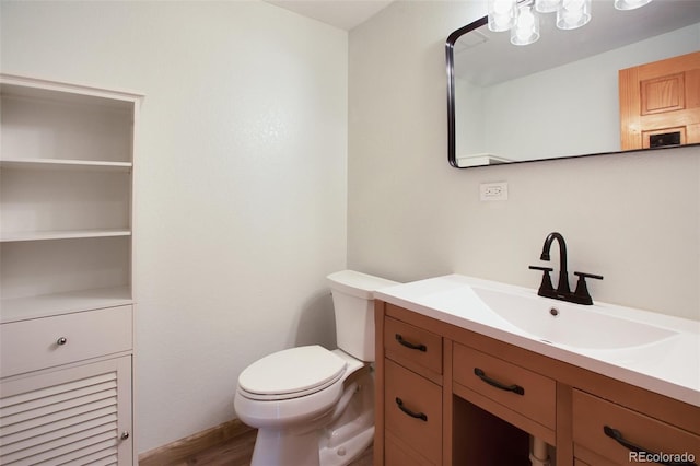 half bath with toilet, vanity, and wood finished floors