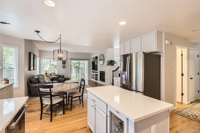 10230 Lauren Ct, Highlands Ranch, CO 80130 - kitchen featuring stainless steel fridge, open floor plan, light wood finished floors, healthy amount of natural light, and recessed lighting