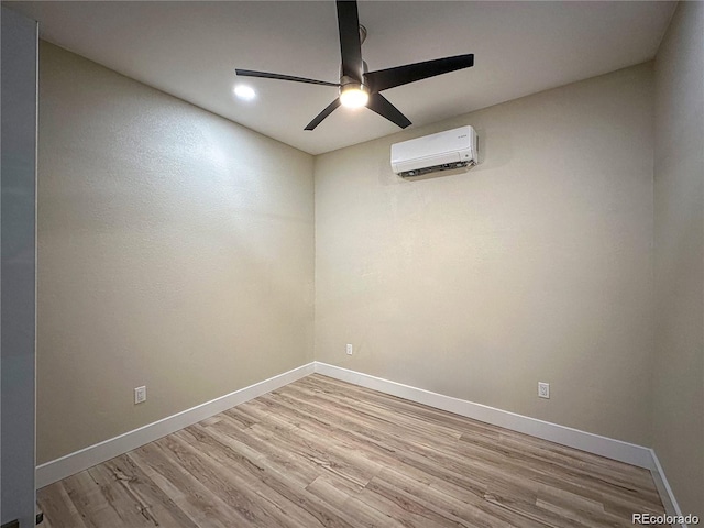 empty room featuring a ceiling fan, a wall mounted air conditioner, baseboards, and wood finished floors