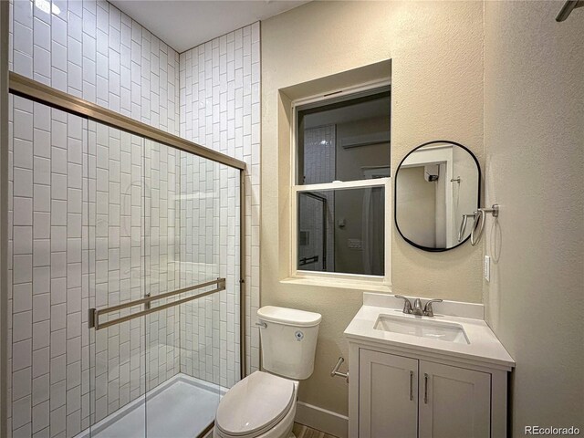 bathroom featuring a shower stall, toilet, and vanity