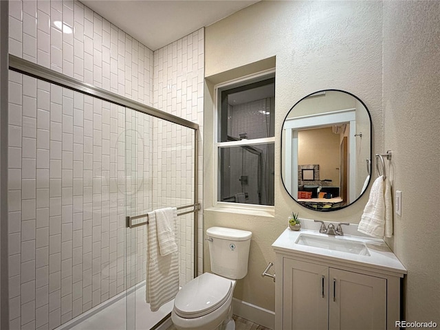 full bath with a textured wall, toilet, vanity, baseboards, and a shower stall