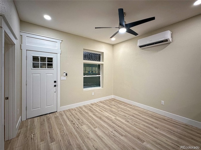 entryway featuring a ceiling fan, an AC wall unit, baseboards, and light wood finished floors