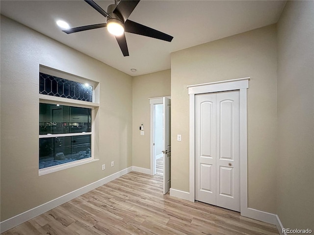 unfurnished bedroom featuring a closet, wood finished floors, a ceiling fan, and baseboards