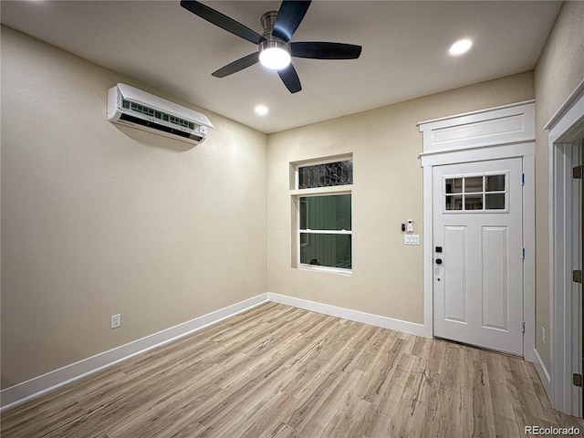 foyer with light wood-style floors, an AC wall unit, ceiling fan, and baseboards