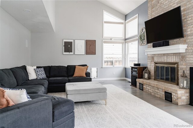 6386 S Pierson St, Littleton, CO 80127 - living area featuring a brick fireplace, wood finished floors, baseboards, and a high ceiling