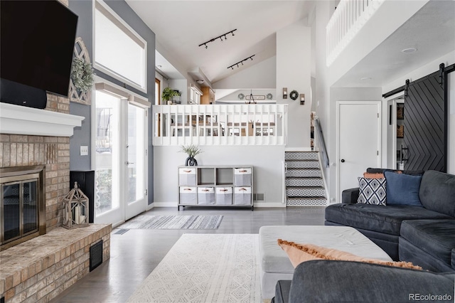 6386 S Pierson St, Littleton, CO 80127 - living area featuring a brick fireplace, a barn door, wood finished floors, track lighting, and high vaulted ceiling