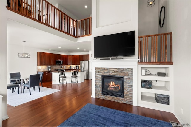 4887 Raven Run, Broomfield, CO 80023 - living room featuring dark wood-style floors, a towering ceiling, a fireplace, recessed lighting, and built in features