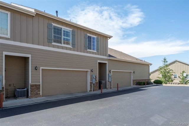 4887 Raven Run, Broomfield, CO 80023 - view of front of home featuring board and batten siding, cooling unit, and stone siding