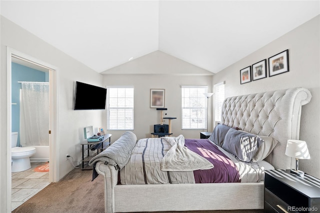 bedroom with light carpet, vaulted ceiling, and ensuite bathroom