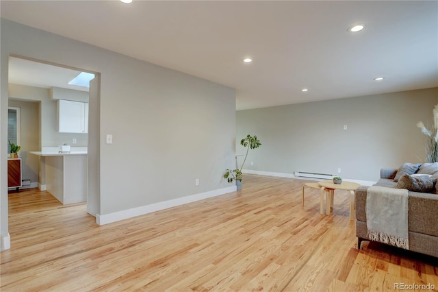 living area featuring recessed lighting, light wood-type flooring, a baseboard heating unit, and baseboards