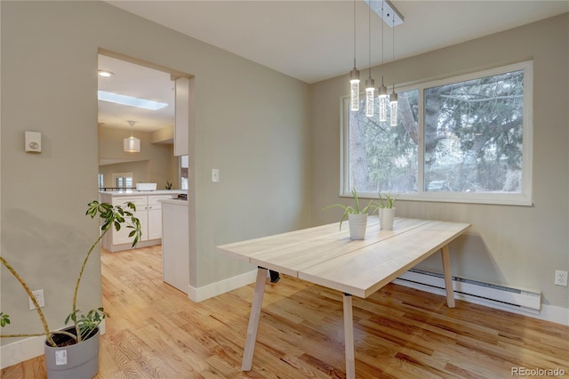 dining room featuring baseboards, a baseboard heating unit, and light wood-style floors