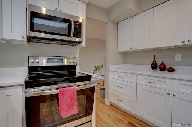 kitchen featuring light wood finished floors, white cabinets, appliances with stainless steel finishes, and light countertops