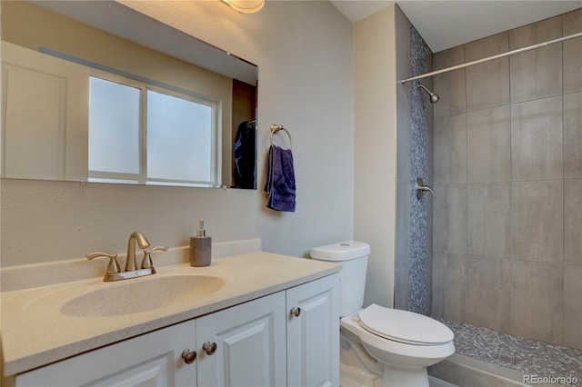 full bath with tiled shower, toilet, and vanity