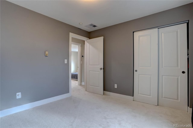 unfurnished bedroom featuring light carpet, visible vents, a closet, and baseboards