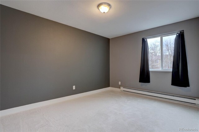 carpeted empty room featuring a baseboard heating unit