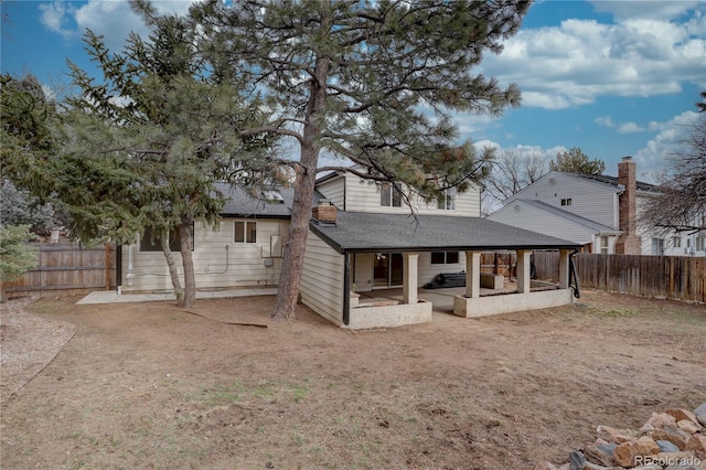 rear view of house with a patio area, a fenced backyard, and roof with shingles