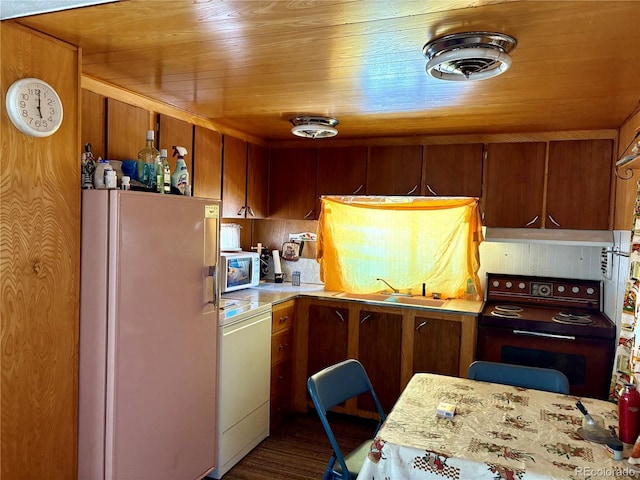 kitchen featuring brown cabinets, a sink, under cabinet range hood, white appliances, and light countertops