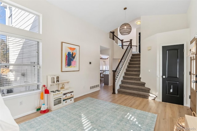 entryway featuring high vaulted ceiling and light wood-type flooring