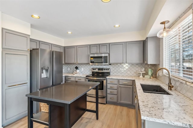 kitchen featuring stainless steel appliances, a breakfast bar, pendant lighting, a kitchen island, and sink