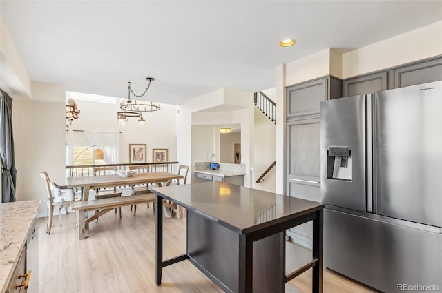 kitchen featuring light hardwood / wood-style flooring, pendant lighting, a notable chandelier, stainless steel refrigerator with ice dispenser, and gray cabinetry