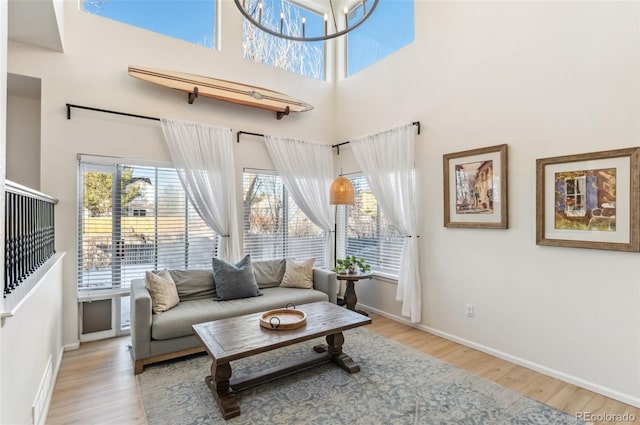 living room featuring light hardwood / wood-style floors, an inviting chandelier, and a high ceiling