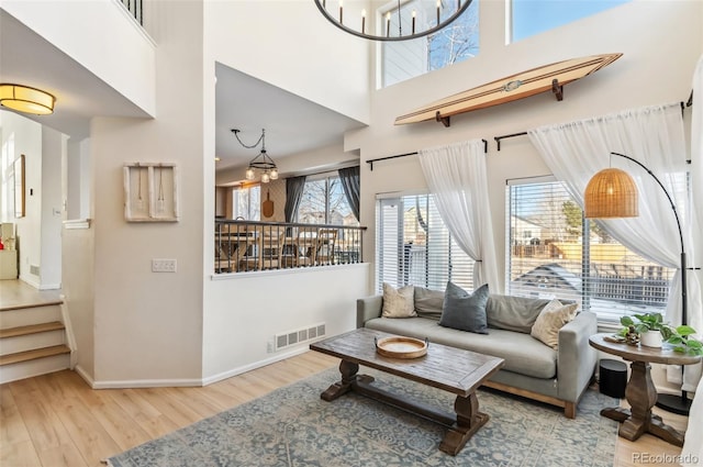 living room with a high ceiling, light wood-type flooring, and a notable chandelier